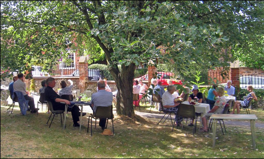 Parishioners enjoy cream teas in the churchyard in the shade of the trees